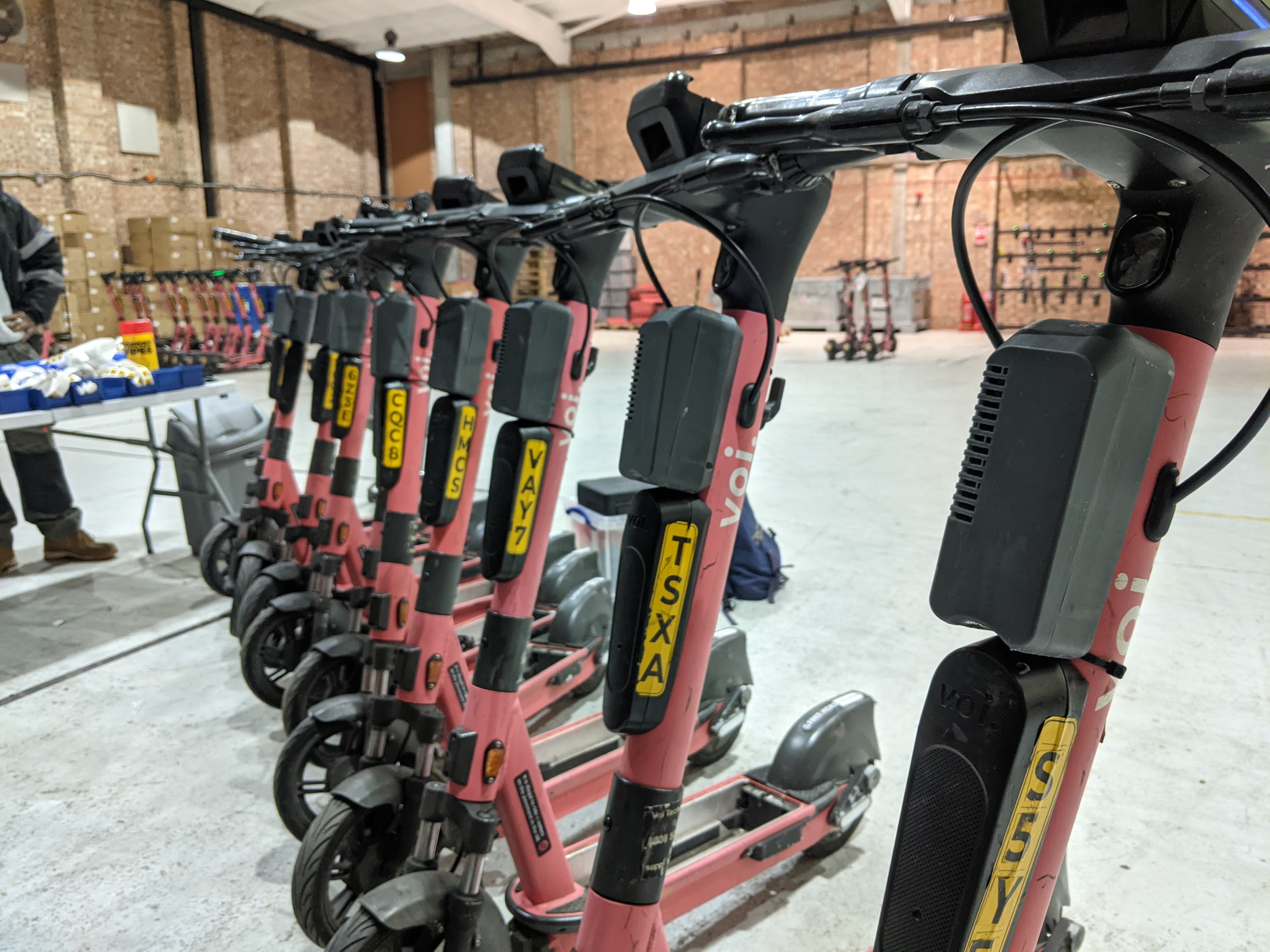 Photo of 10 e-scooters with sensors attached, lined up in Voi depot